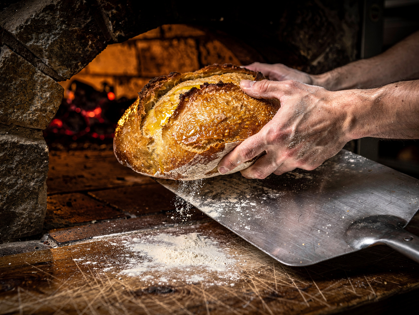 Artisan sourdough bread baking inside a rustic wood-fired outdoor clay oven
